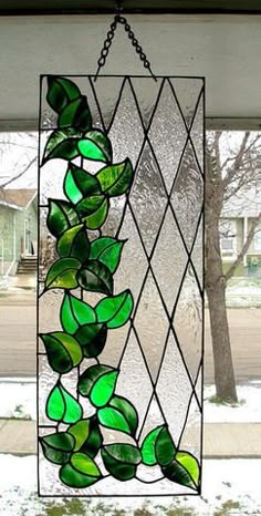 a stained glass window with green leaves hanging from it's side in front of a house