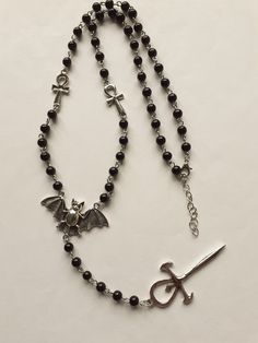 Gothic black and silver rosary style necklace. 6mm black acrylic beads individually linked to form the rosary chain, with silver ankh detail on each side. Also silver colour bat and beads leading to silver colour ankh/cross pendant. Lobster clasp fastening. Chain length 60cm/17 1/2 inches with extension chain, cross/ankh pendant 60 x 28mm, bat 28x46mm (measurements are approximate). On dispatch this item will be carefully wrapped in tissue paper before being sent in a padded envelope for extra p Rosary Style Necklace, Ankh Pendant, Silver Rosary, Ankh Cross, Rosary Chain, Silver Colour, Black Acrylic, Black Acrylics, Style Necklace