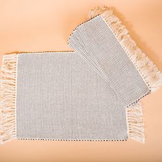 two gray and white towels laying on top of each other next to an orange wall