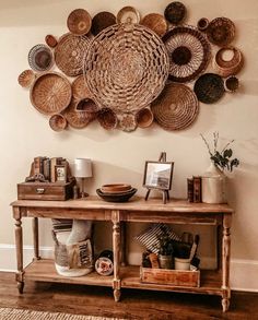 a wooden table topped with baskets on top of it next to a wall mounted art piece