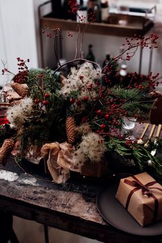 a wooden table topped with lots of christmas decorations next to a brown box filled with presents