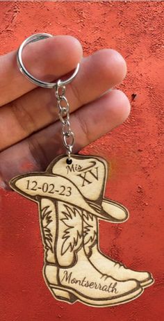 a hand holding a keychain with an image of a cowboy boot on it