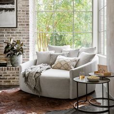 a living room filled with furniture and a large window next to a brick wall in front of it