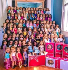 a large group of dolls sitting on top of each other in front of a pile of boxes