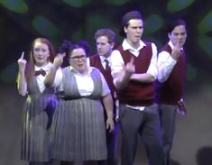 a group of people standing on top of a stage with their hands in the air