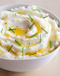 mashed potatoes in a white bowl topped with green chives