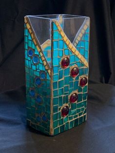 a blue vase with red and yellow designs on it sitting on a black tablecloth