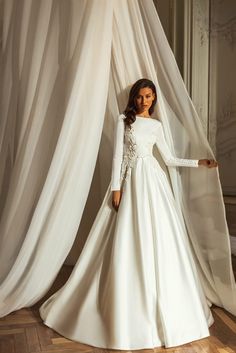 a woman in a white wedding dress standing next to a curtain