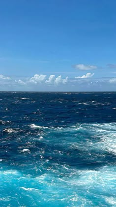 the ocean is blue and choppy with white clouds