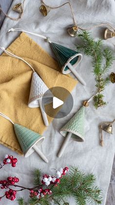 christmas decorations on a table with bells and pine cones in the middle, surrounded by evergreen branches