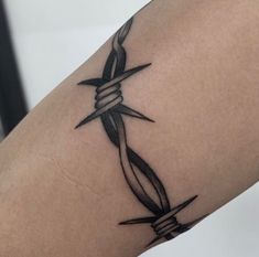 a tattoo on the arm of a person with barbed wire and scissors attached to it