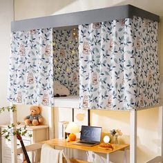 a laptop computer sitting on top of a wooden desk under a window covered in curtains