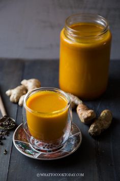 a glass cup filled with orange juice next to some spices