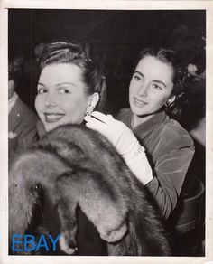 an old photo of two women sitting next to each other at a party with fur stolers around their necks