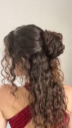 the back of a woman's head with long curly hair in a red dress