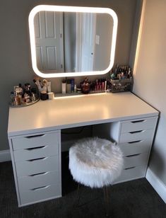 a white vanity with a mirror and stool