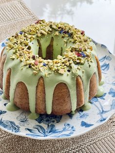 a bundt cake with green frosting and nuts on top sitting on a plate