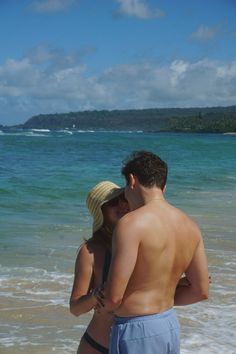 a man and woman standing in the ocean