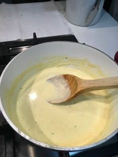 a wooden spoon is in a saucepan on the stove top, with melted cheese