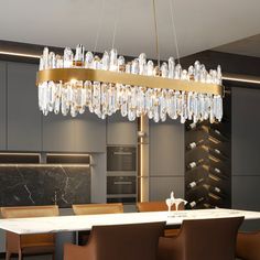 an elegant chandelier hangs from the ceiling in a modern kitchen with marble counter tops and brown leather chairs