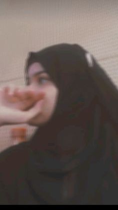 a blurry image of a woman eating food on the floor with her hand in front of her face