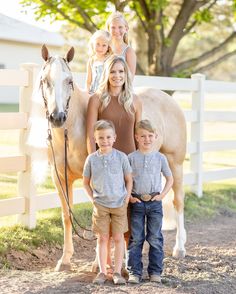 a woman and two children standing next to a horse