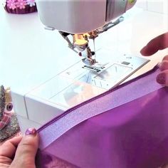 someone is using a sewing machine to sew something with purple ribbon on the table