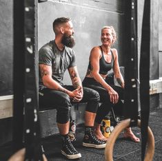 a man and woman sitting on top of a bench in front of a gym wall