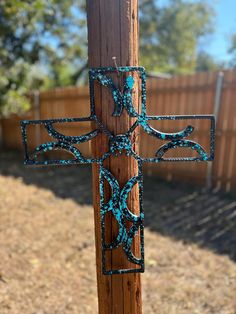 a cross made out of metal sitting on top of a wooden pole