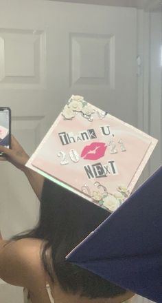 a woman taking a selfie in front of a mirror with a graduation cap on her head