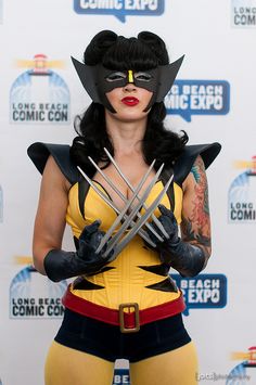 a woman dressed in wolverine costume with claws on her chest and black hair, holding two knives