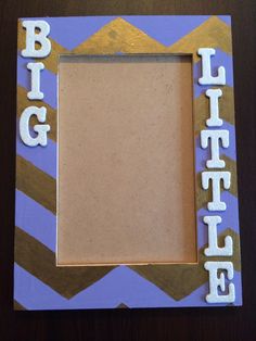 a photo frame with the word big sister spelled in white letters on it, sitting on a table