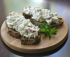 a wooden plate topped with two pieces of bread covered in cream cheese and garnished with parsley