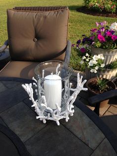 a candle sits on an outdoor table with flowers in the background