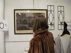 a woman looking at art on display in a store