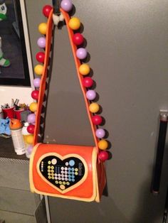 an orange purse hanging from the side of a refrigerator freezer with beads on it