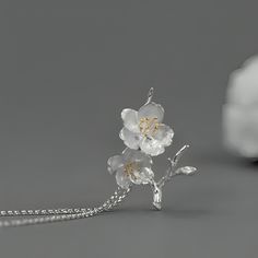 Introducing our exquisite pendant featuring a delicate design of cherry blossoms crafted in sterling silver. The intricate details of the flowers are beautifully highlighted with gold plating on the stamens, adding a touch of elegance and sophistication. The pendant captures the essence of spring, symbolizing renewal and beauty. It hangs gracefully from a matching sterling silver chain, making it a timeless accessory suitable for any occasion. Delicate Spring Jewelry For Anniversary, Delicate Jewelry For Spring Anniversary, Delicate Jewelry For Anniversary In Spring, Delicate White Gold Flower Pendant Necklace, Elegant Blossom Flower Pendant Jewelry, Elegant Blossom Color Flower Pendant Jewelry, Dainty Blossom-colored Jewelry For Anniversary, Dainty Blossom Color Jewelry For Anniversary, Elegant Sterling Silver Spring Jewelry