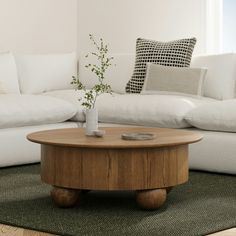 a living room with white couches and a wooden coffee table