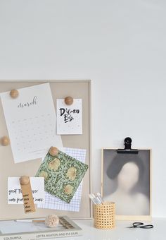 a white desk topped with lots of papers and magnets next to a framed photo