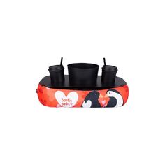 two black cups are sitting on top of an inflatable boat with penguins and hearts