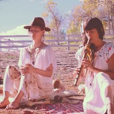 two women sitting on the ground playing instruments