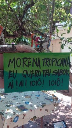 a green sign sitting on top of a table under a tree