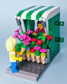 a lego man standing in front of a flower stand with flowers and plants on it