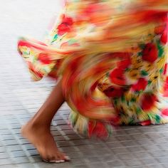 a woman in a colorful dress is walking down the street with her legs spread out