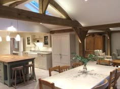 an open kitchen and dining room area with white walls, wood beams and flooring