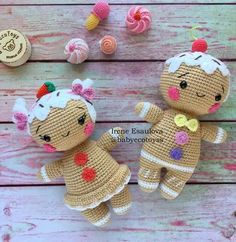 two crocheted dolls sitting next to each other on a wooden table with candy candies