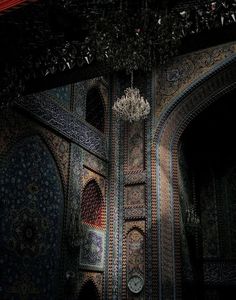 a chandelier hanging from the ceiling in a room with intricately decorated walls