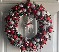 a christmas wreath on the front door with ornaments around it and an ornament