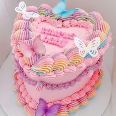 a pink heart shaped cake with butterflies on top