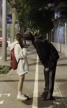 a man kissing a woman on the side of a road next to a cross walk